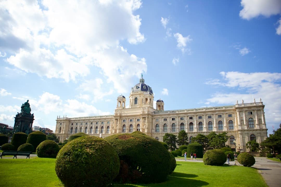 Wiedeńskie muzeum, klasyczna architektura, zielony park, słoneczny dzień, błękitne niebo.