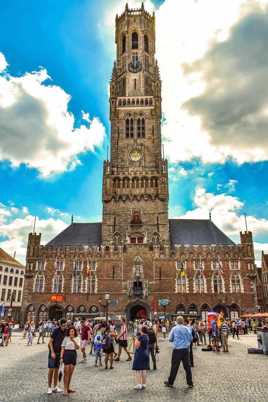 Historyczna Dzwonnica w Brugii na placu Markt, słoneczny dzień, turyści.