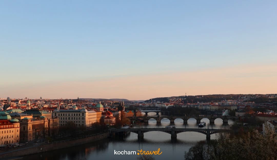 Panorama Pragi z rzeką Wełtawą i mostami o zachodzie słońca.