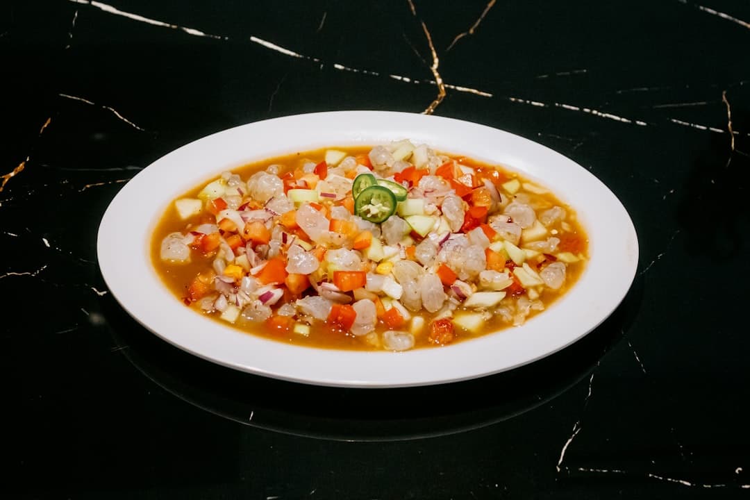 Ceviche z krewetek z warzywami i papryczkami jalapeño na czarnym marmurze.