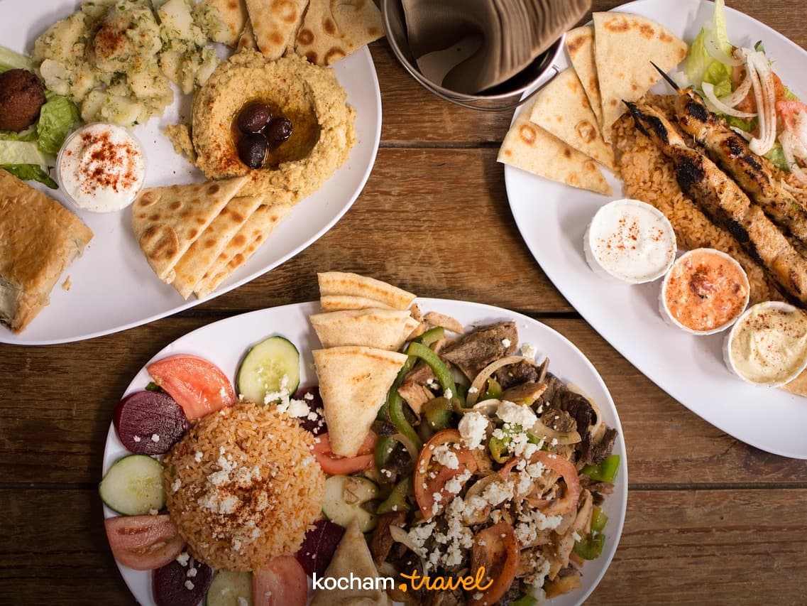 Kuchnia śródziemnomorska, hummus, szaszłyki, gyros, pita na drewnianym stole.