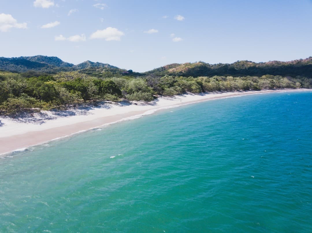 Rajska tropikalna plaża z turkusową wodą i zielonymi wzgórzami.