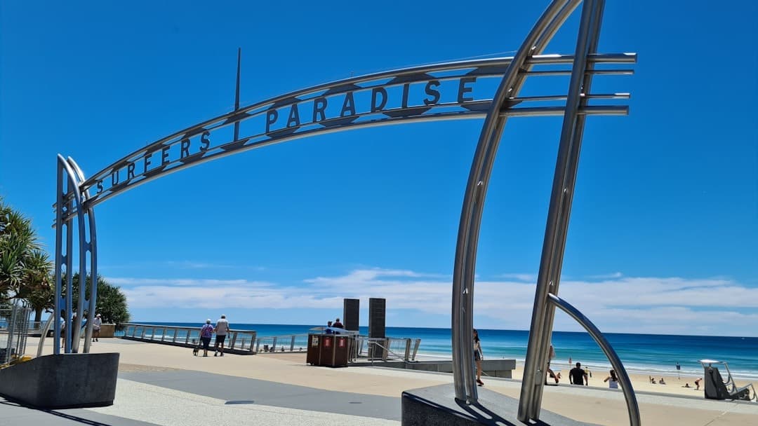 Słoneczna plaża Surfers Paradise, znak, promenada i lazurowy ocean.