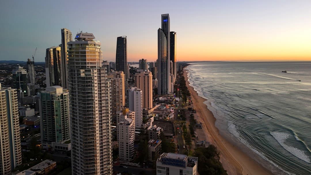 Panoramiczny widok miasta, wieżowców, plaży i oceanu o zachodzie słońca.