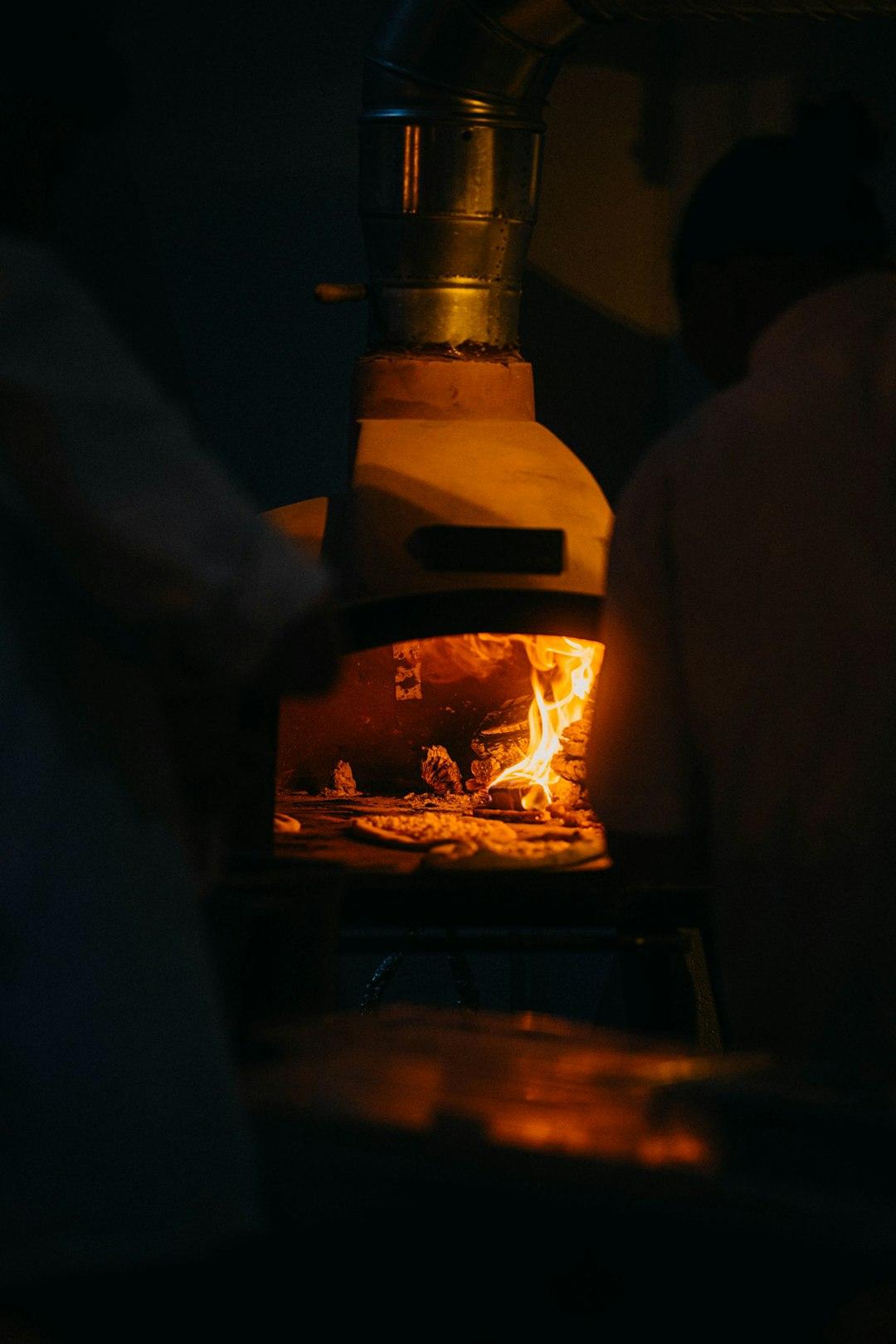 Pizza pieczona w tradycyjnym piecu opalanym drewnem, płomienie.