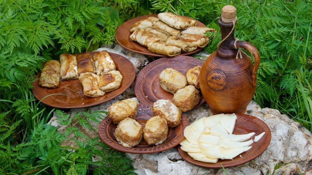 Tradycyjne placki, ziemniaki, ser, dzbanek na glinianych talerzach w naturze.