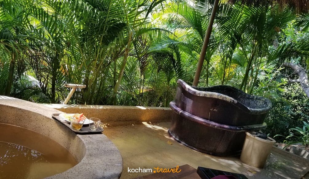 Relaksujące tropikalne spa z wannami i owocami wśród palm.