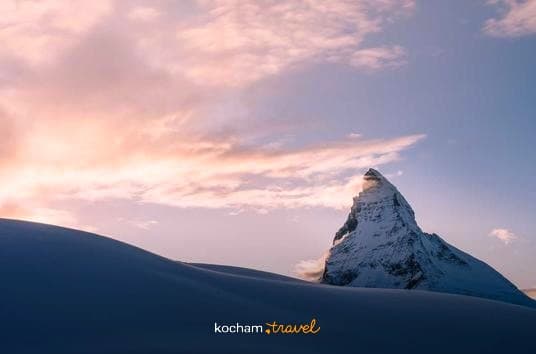 Ośnieżony szczyt Matterhorn na tle różowych chmur o wschodzie słońca.